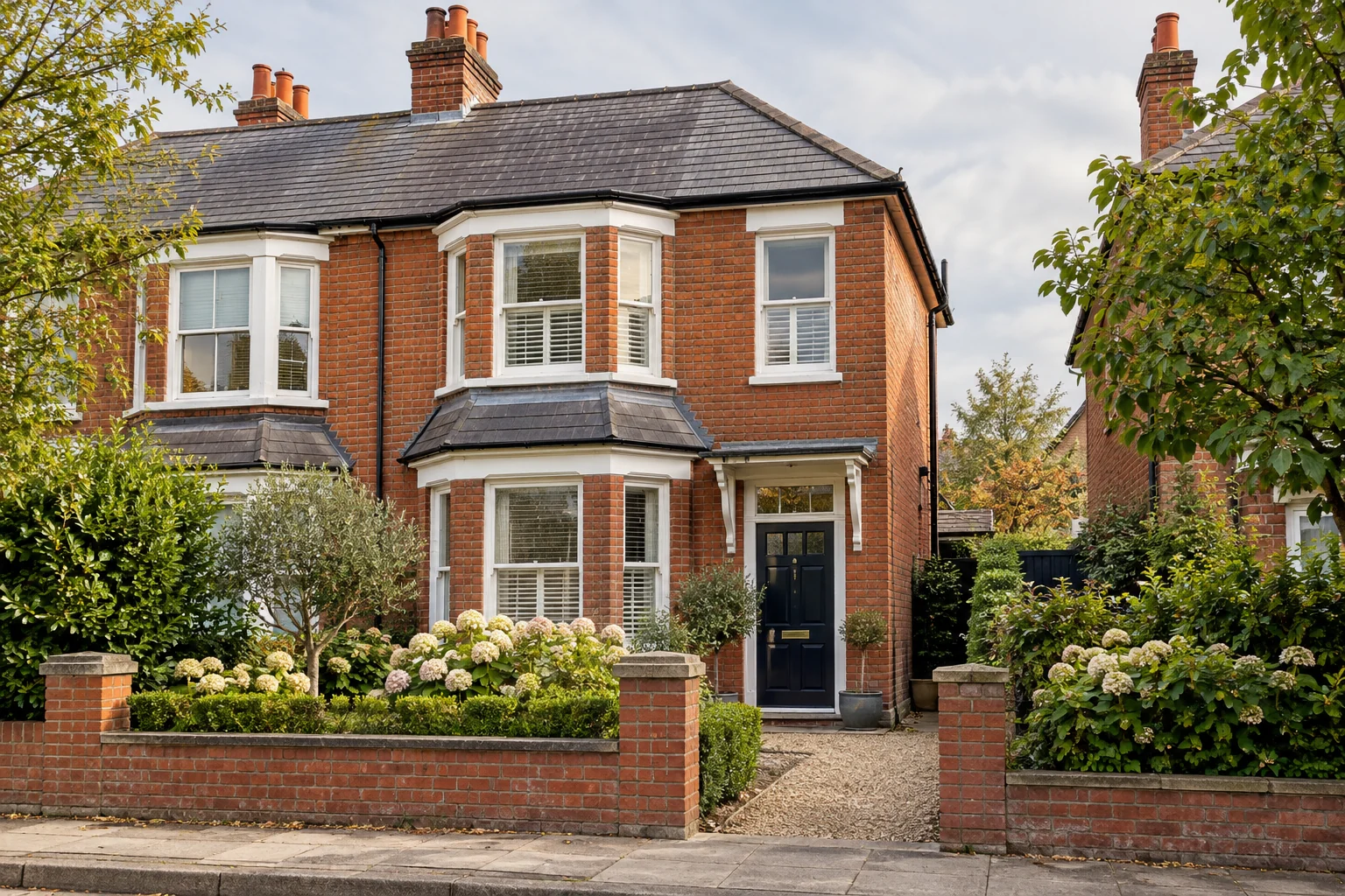 Red-brick British home with a leafy front garden